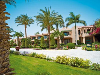 Hotel grounds with palm trees, well-maintained lawns, and a bright blue sky.