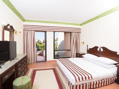 Helles Hotelzimmer mit Doppelbett, TV, Balkon und gestreifter Dekoration