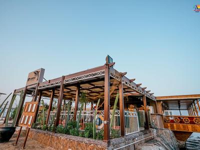 Moderner Außenbereich eines Hotels mit Holzstruktur und Glasgeländer bei klarem Himmel.