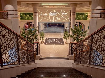 Elegante Hotellobby mit Treppen, Pflanzen und dekorativer Beleuchtung.