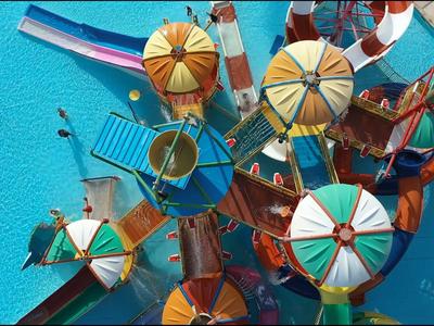 Bunte Sonnenschirme und Liegestühle an einem Pool aus der Vogelperspektive