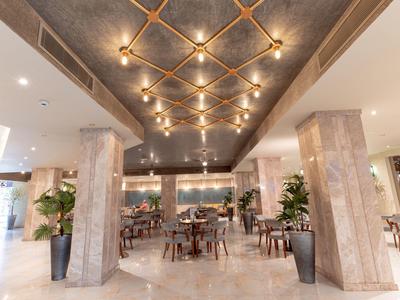 Eleganter Hotelrestaurantbereich mit Marmorboden, Säulen und gedeckten Tischen unter warmem Decklicht.