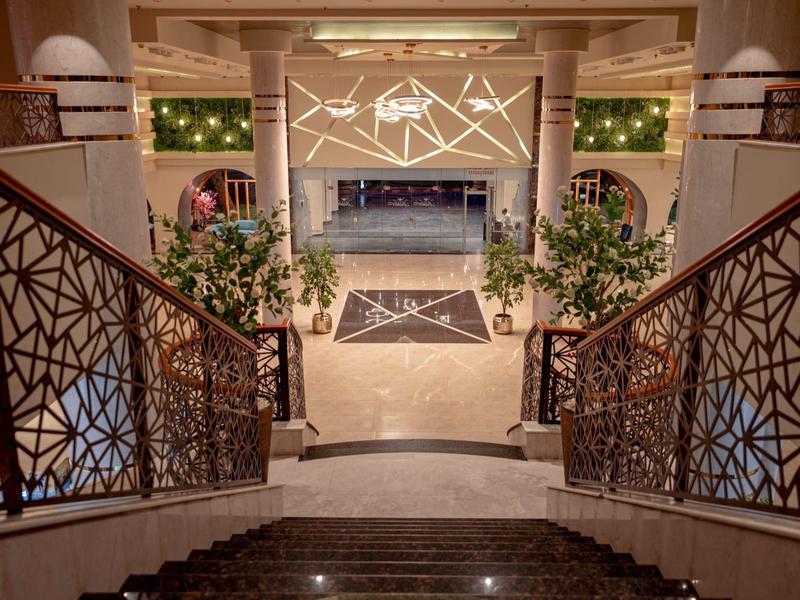 Elegante Hotellobby mit Treppen, Pflanzen und dekorativer Beleuchtung.