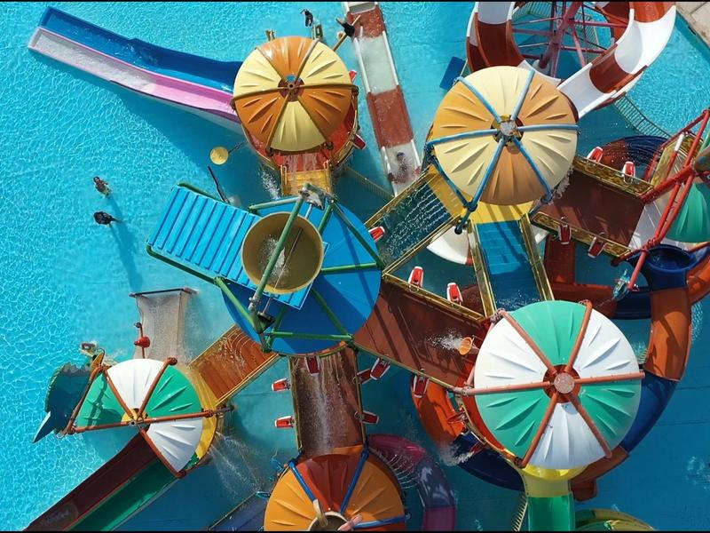 Bunte Sonnenschirme und Liegestühle an einem Pool aus der Vogelperspektive