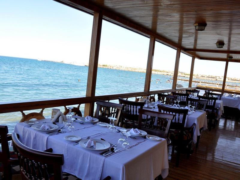 Blick auf gedeckte Tische auf einer überdachten Terrasse mit Meerblick.