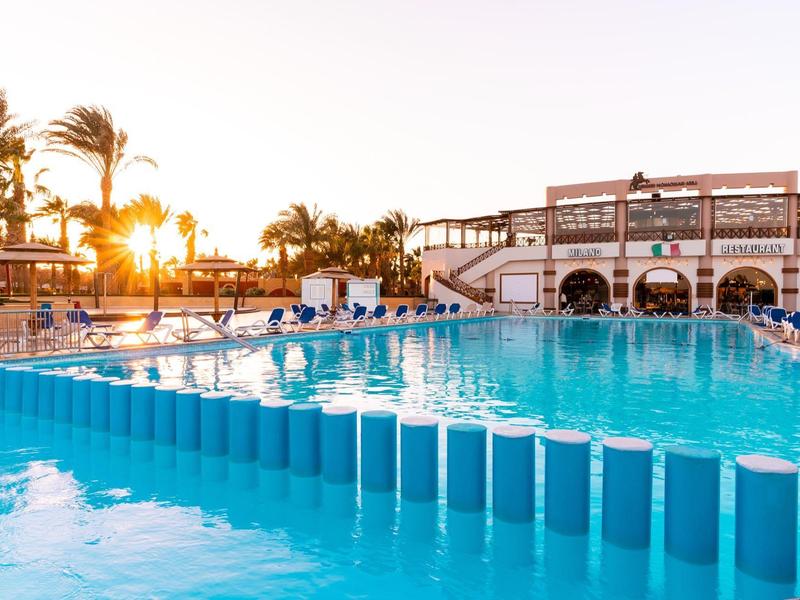 Außenpool bei Sonnenuntergang mit blauen Schwimmbahnen und einem Gebäude im Hintergrund.