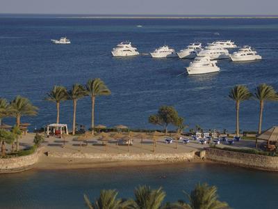 Zona costera con palmeras y botes en el mar azul en día despejado