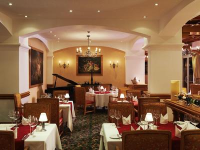 Restaurante elegante con mesas preparadas, candelabros y un piano de cola al fondo.