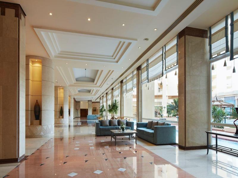 Spacious hotel lobby with marble floor, large windows, and modern seating area.