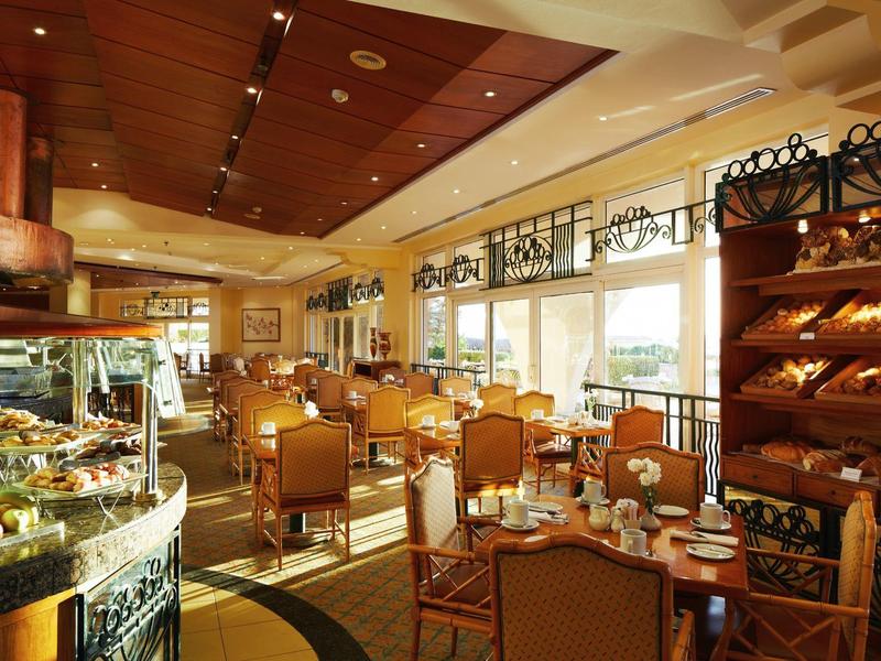 Bright restaurant with wooden furniture and large windows, offering a warm and cozy dining area.