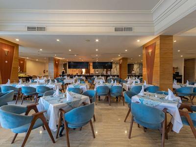 Modernes Restaurant mit blauen Sesseln und weiß gedeckten Tischen in einem Hotel.