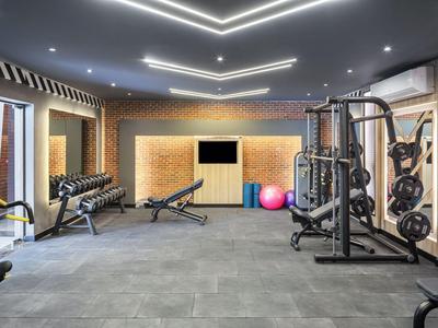 Moderner Fitnessraum mit Gewichten, Trainingsgeräten und Sportbällen in einem Hotel.