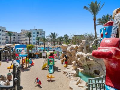 Bunter Hotelspielplatz mit Rutschen, Sand und Palmen unter blauem Himmel.