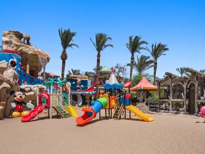 Bunter Kinderspielplatz mit Rutschen, Palmen und Felsenstrukturen im sonnigen Hotelbereich.