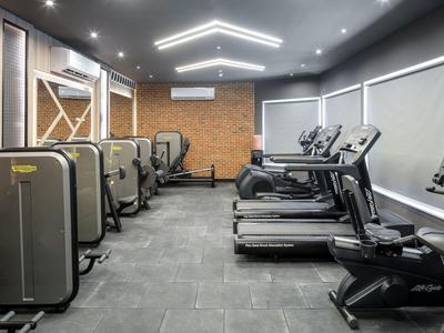 Moderner Hotel-Fitnessraum mit Laufbändern, Kraftgeräten und gedämpfter Beleuchtung.