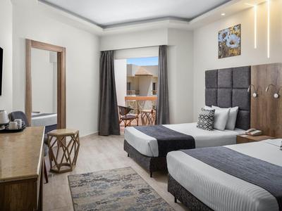 Chambre d'hôtel moderne avec deux lits simples, balcon et vue sur une terrasse.