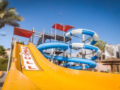 Yellow water slides with blue spiral slides and palm trees at a holiday resort waterpark.