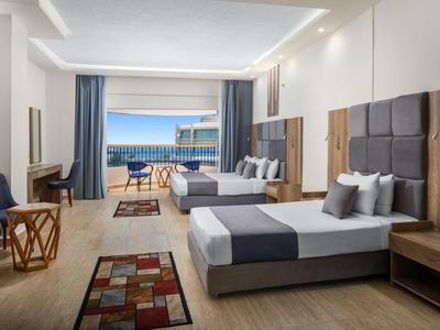 Chambre d'hôtel moderne avec deux lits, balcon et vue sur la mer.