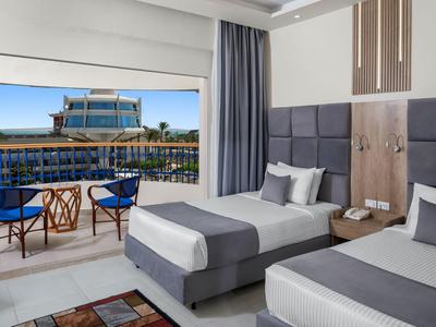 Chambre d'hôtel moderne avec deux lits simples, balcon et vue sur une piscine.