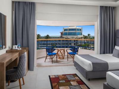 Chambre d'hôtel moderne avec lit double, balcon et vue sur la piscine et les environs.