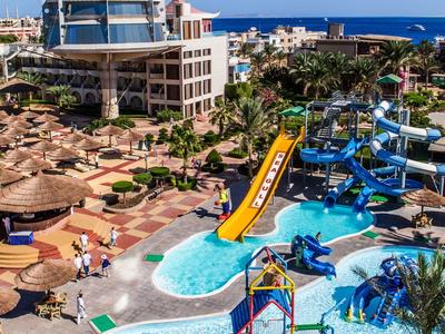 Ein farbenfroher Wasserpark mit Rutschen, Pools und Palmen unter klarem blauem Himmel.