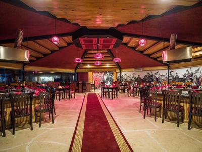 Large decorated dining hall with long wooden tables, chairs, and red carpet in the center.