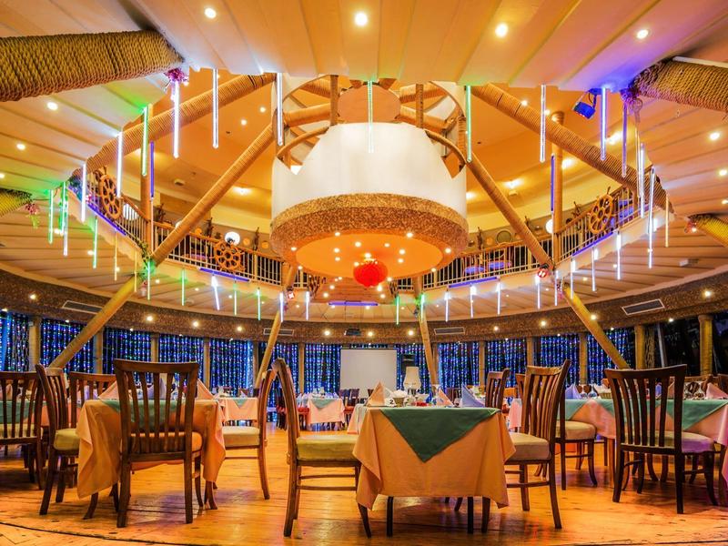 Elegantes Restaurant mit rundem Holzdach, festlicher Beleuchtung und gedeckten Tischen in warmem Licht.