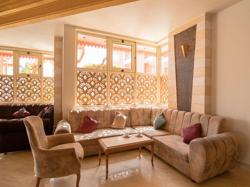 Helles Wohnzimmer mit beiger Eckcouch, Sessel, Holztisch und dekorativer Wandverkleidung.