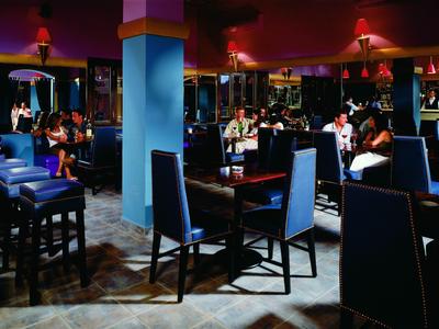 Intérieur d'un restaurant cosy avec des chaises bleues et des tables sous un éclairage tamisé