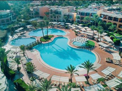 Grand piscine extérieure avec transats et palmiers dans une station balnéaire tropicale.