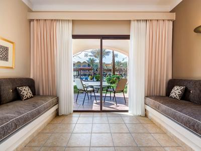 Bright room with two brown sofas and access to a terrace overlooking a pool.