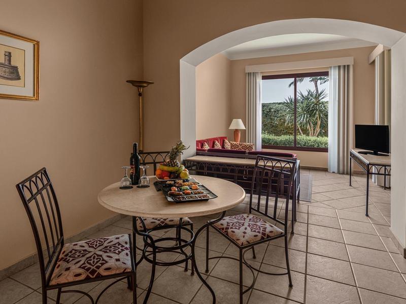 Cozy dining area with a view of a terrace and palm trees in the background.