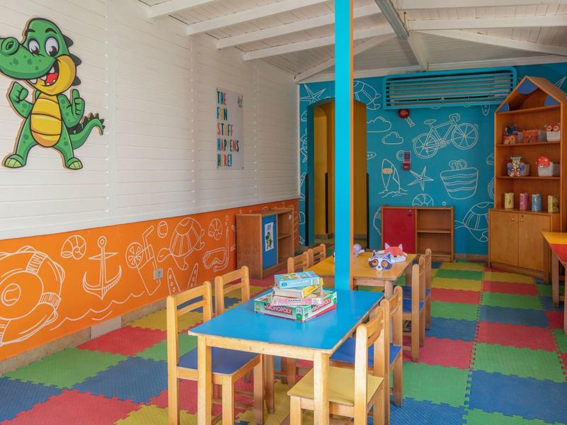 Colorful children's playroom with tables, chairs, and wall murals in the hotel.