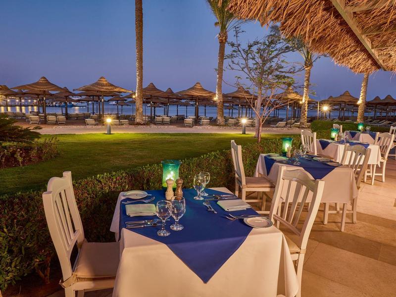 Evening terrace with set tables overlooking the beach with umbrellas