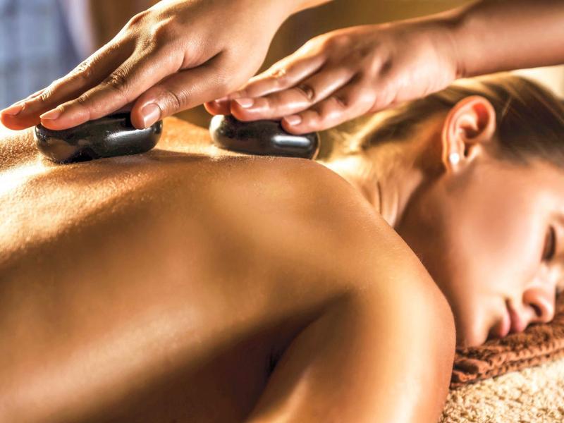 Woman receiving hot stone massage, relaxed atmosphere, wellness and relaxation.
