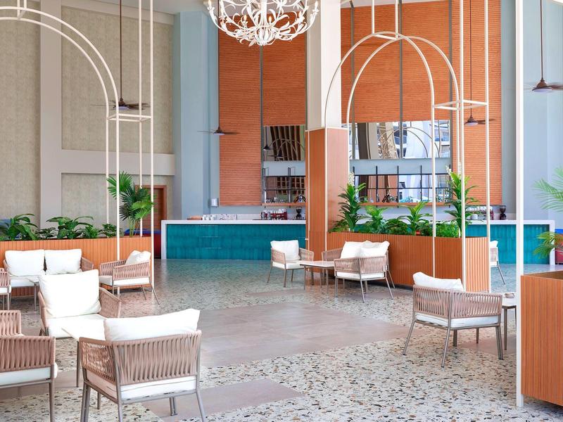 Heller moderner Lounge-Bereich mit Holz, weißen Sesseln, Pflanzen und gemustertem Bodenbelag.