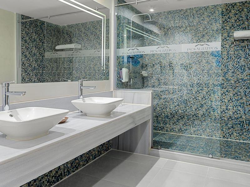 Modernes Badezimmer mit zwei weißen Waschbecken, großem Spiegel und Glas-Duschkabine mit blauer Kachelwand.