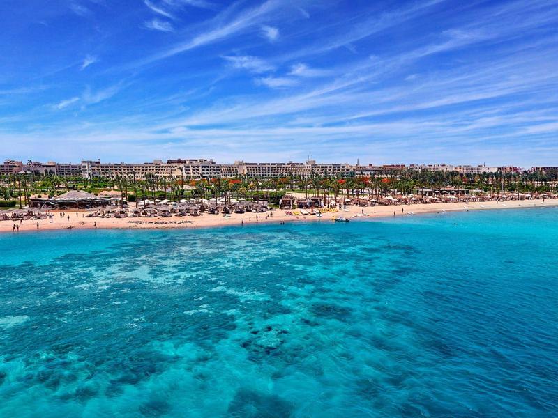 Wide beach with clear turquoise water under a blue sky.