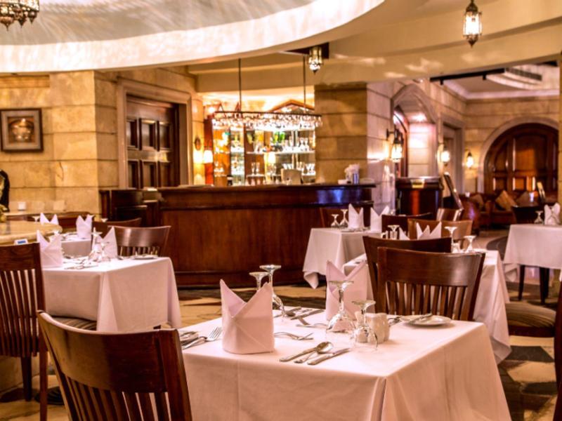 Elegantes Restaurant mit weißen Tischdecken, gedämpftem Licht und Holzmöbeln in warmen Tönen.