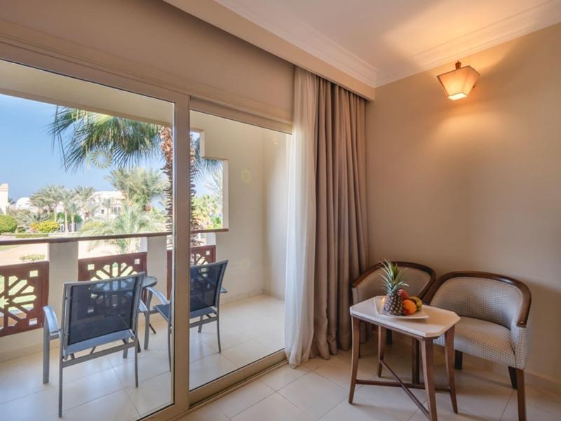 Heller Raum mit großem Glasfenster, Balkon mit Stühlen, kleinem Tisch und einer Pflanze drinnen.