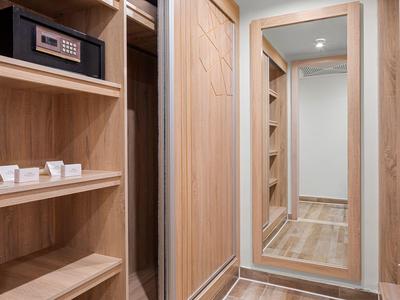 Kleiderschrank mit Holzregalen, Safe und großem Spiegel, der den Flur reflektiert.