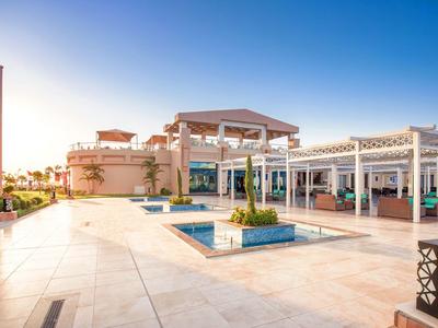 Open hotelruimte met buitenzwembad en moderne zitplaatsen bij zonsondergang.