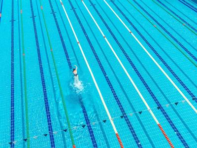 Plavec v prázdném venkovním pruhu velkého modrého bazénu.