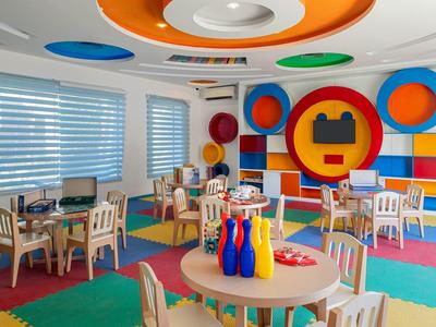 Bunter Spielraum mit Tischen, Stühlen und bunten Bowling-Kegeln in einem Ferienhotel.