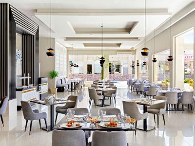 Nowoczesna, jasna restauracja z dużymi oknami i elegancko nakrytymi stolikami.