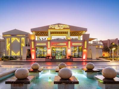 Wyróżniający się budynek hotelu z nowoczesnym designem i podświetlonym zbiornikiem wodnym na pierwszym planie.