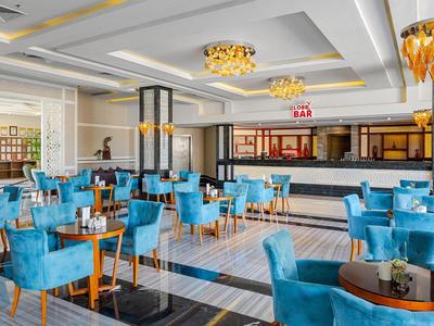 Nowoczesny bar hotelowy z niebieskimi krzesłami i czarnymi stołami.