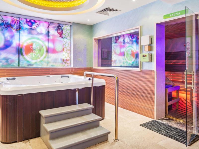 Moderner Wellnessbereich mit Whirlpool und Sauna, Holzverkleidung und farbiger Beleuchtung.