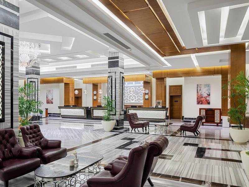 Großer moderner Lobbybereich mit bequemen Ledersesseln, Marmorboden und eleganter Beleuchtung.