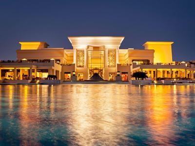 Beleuchtetes Hotel am Wasser bei Nacht mit Spiegelung im ruhigen See.